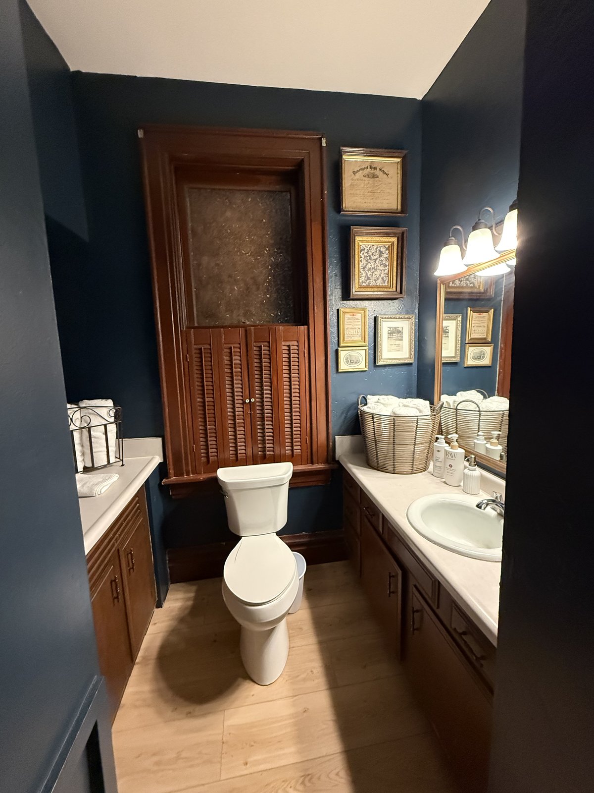 Bathroom — dark walls, vintage framed art, dark wood trim