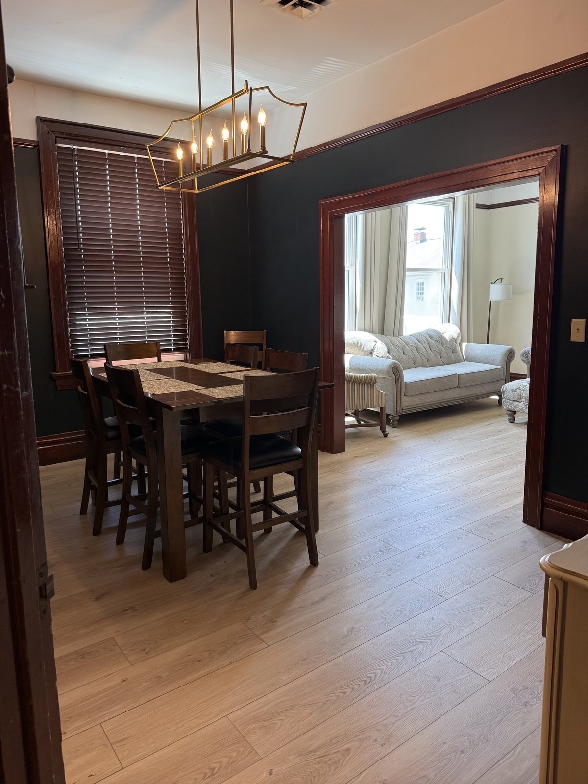 Dining room — dark walls, wood table, pendant chandelier